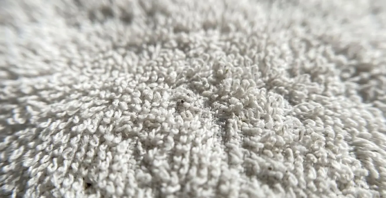 Gros plan extrême sur la texture d'un tissu éponge blanc révélant la structure détaillée des boucles absorbantes et la longueur visible des fibres naturelles